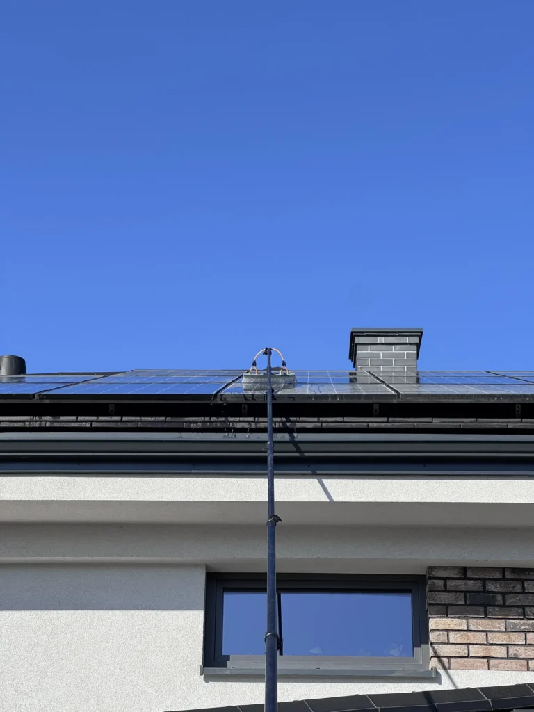 Ściąganie zanieczyszczeń smogu ze szkła modułów PV przy użyciu szczotki na teleskopowej lancy doprowadzającej czystą wodę.