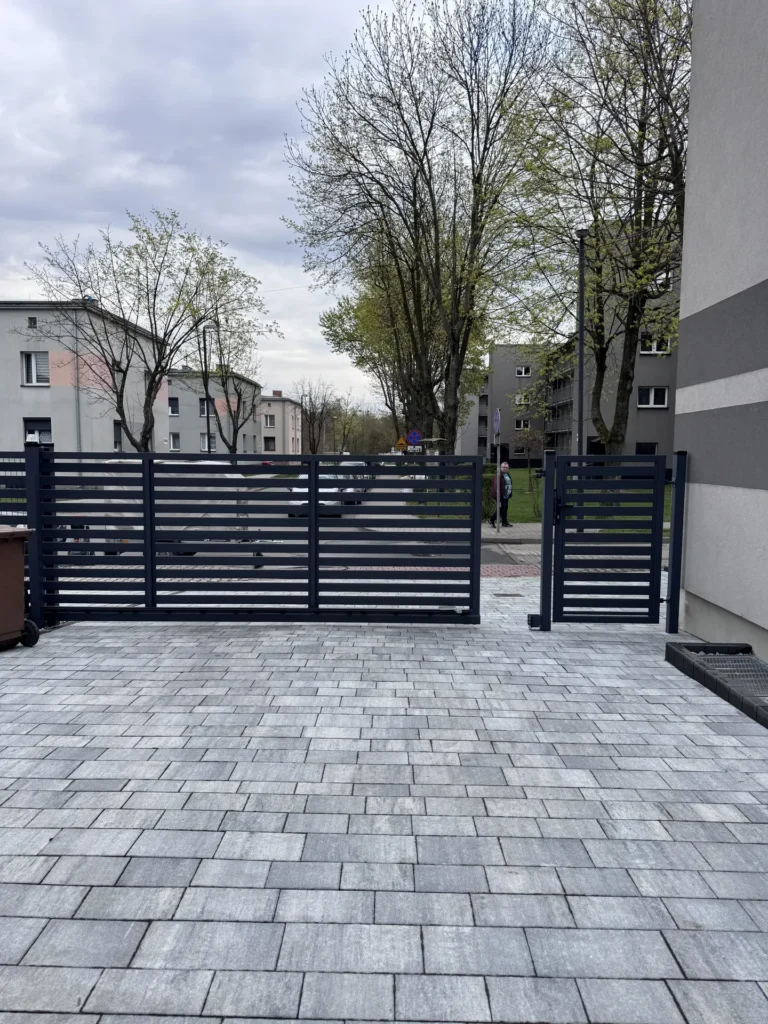 Estetyczny, pozbawiony trawy i mchu wjazd z umytej szarej kostki betonowej.