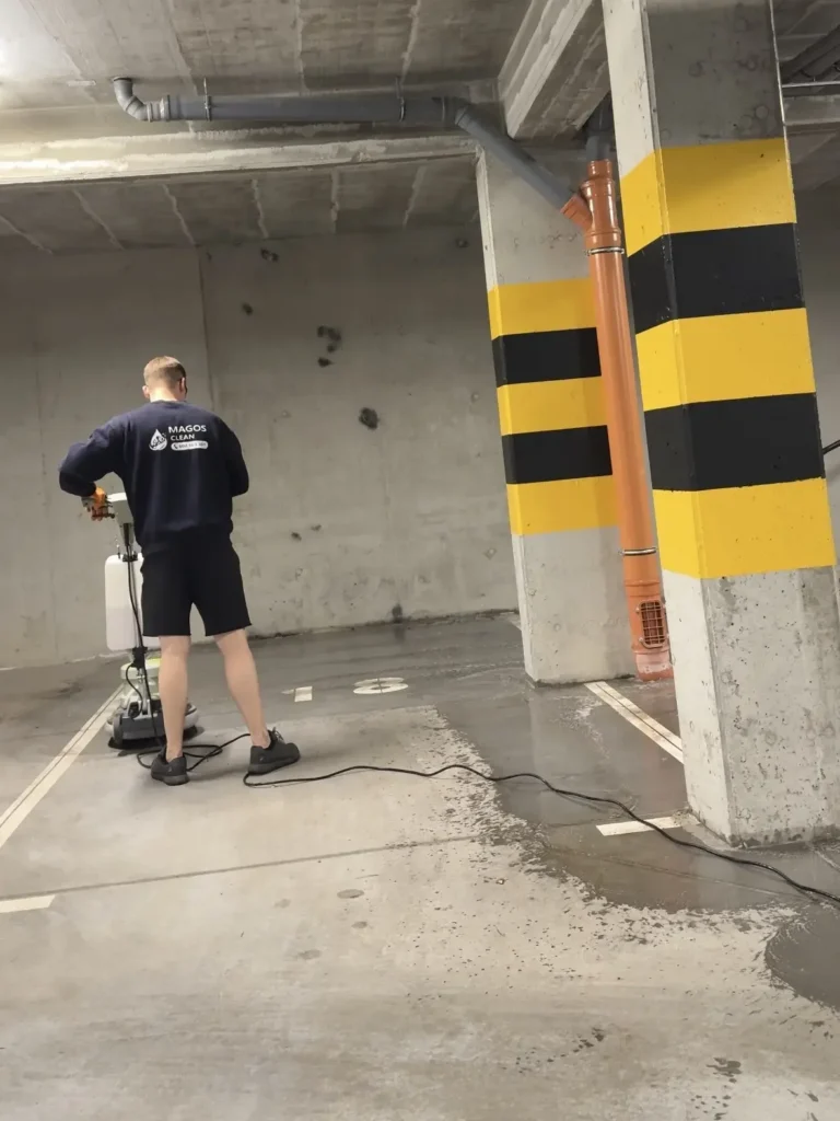 Operator MagosClean doprowadzający strefę parkowania do perfekcyjnej czystości za pomocą przemysłowej szorowarki prowadzonej.